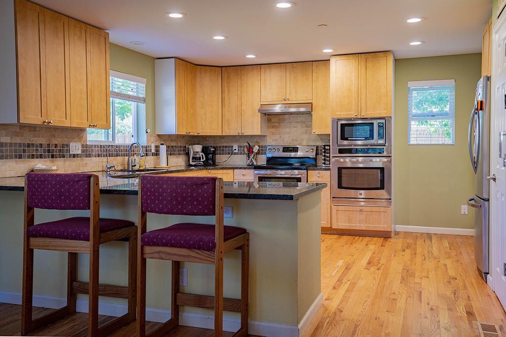 A modern kitchen with wooden cabinets, stainless steel appliances, and a kitchen island with bar stools.