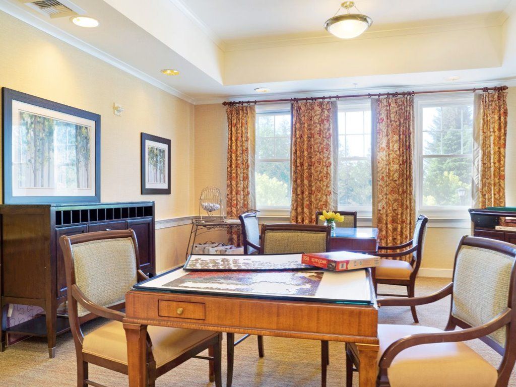 A cozy room with a table and chairs, decorated with curtains and framed artwork.