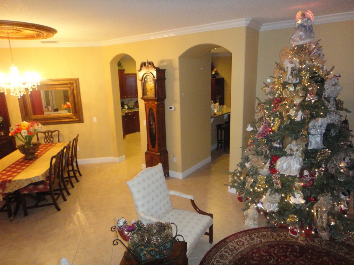 A warmly decorated living and dining area featuring a Christmas tree and a grandfather clock.