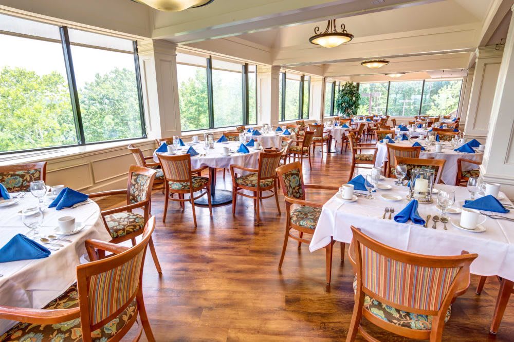 Spacious dining area with neatly set tables by large windows.