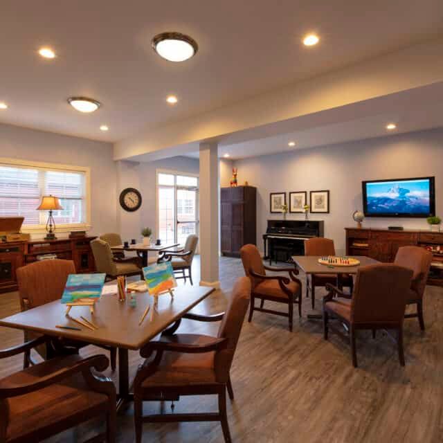 A cozy and well-lit living room with multiple seating areas, a TV, and a fireplace.