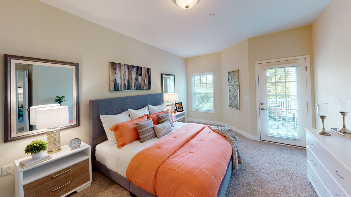 A modern bedroom with orange accents and stylish decor.