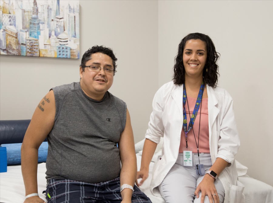 A doctor and patient pose together in a medical setting.