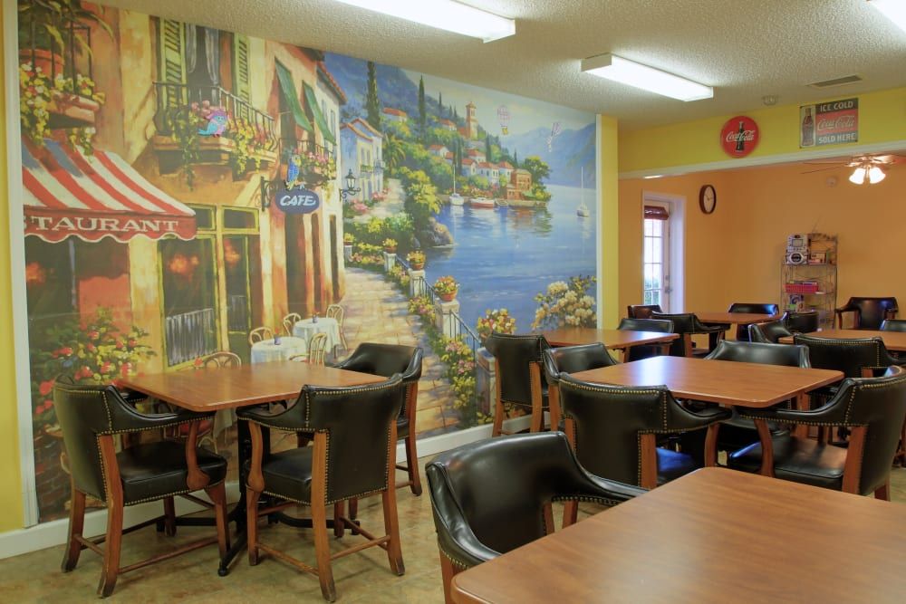 A cozy cafe interior with a colorful mural on the wall and neatly arranged tables and chairs.