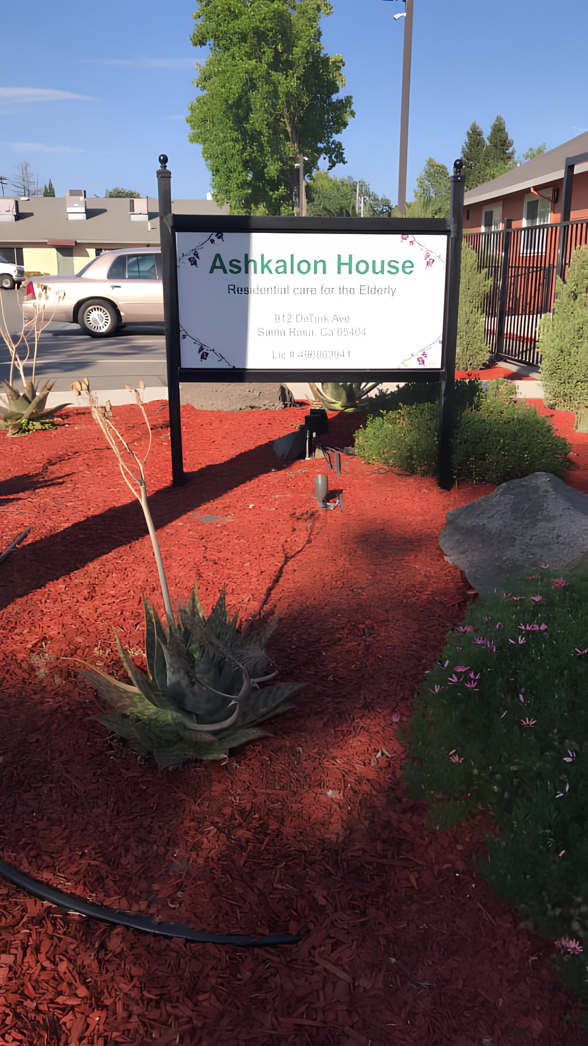 A sign for Arbuckle House surrounded by landscaped mulch and an aloe plant.