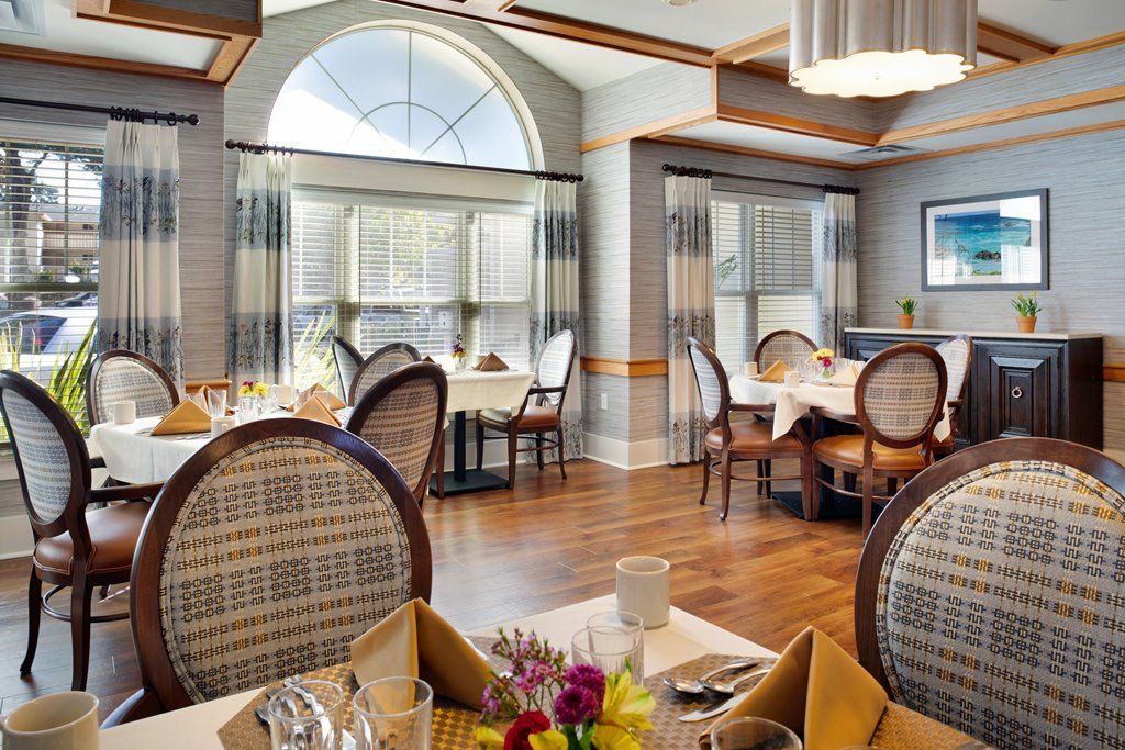 Elegant dining room with neatly arranged tables and chairs, featuring a large window and tasteful decor.