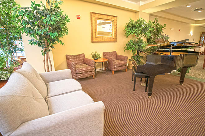 A cozy lobby with a grand piano and comfortable seating surrounded by indoor plants.