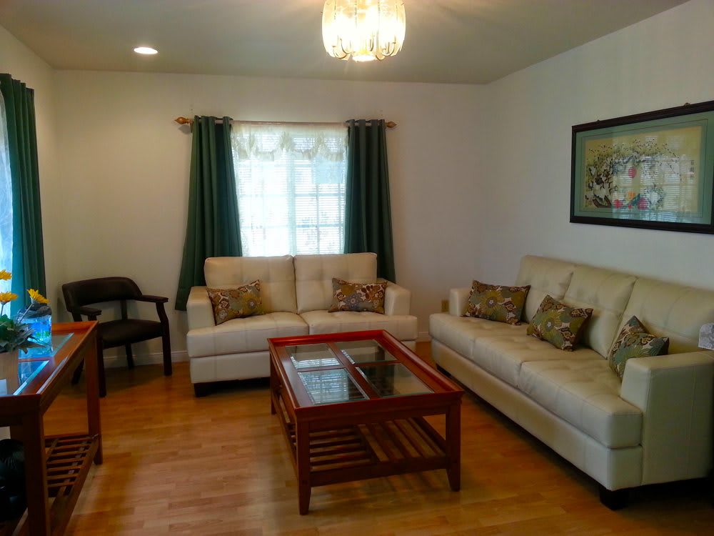 A cozy living room with two cream-colored sofas, a wooden coffee table, and dark green curtains.