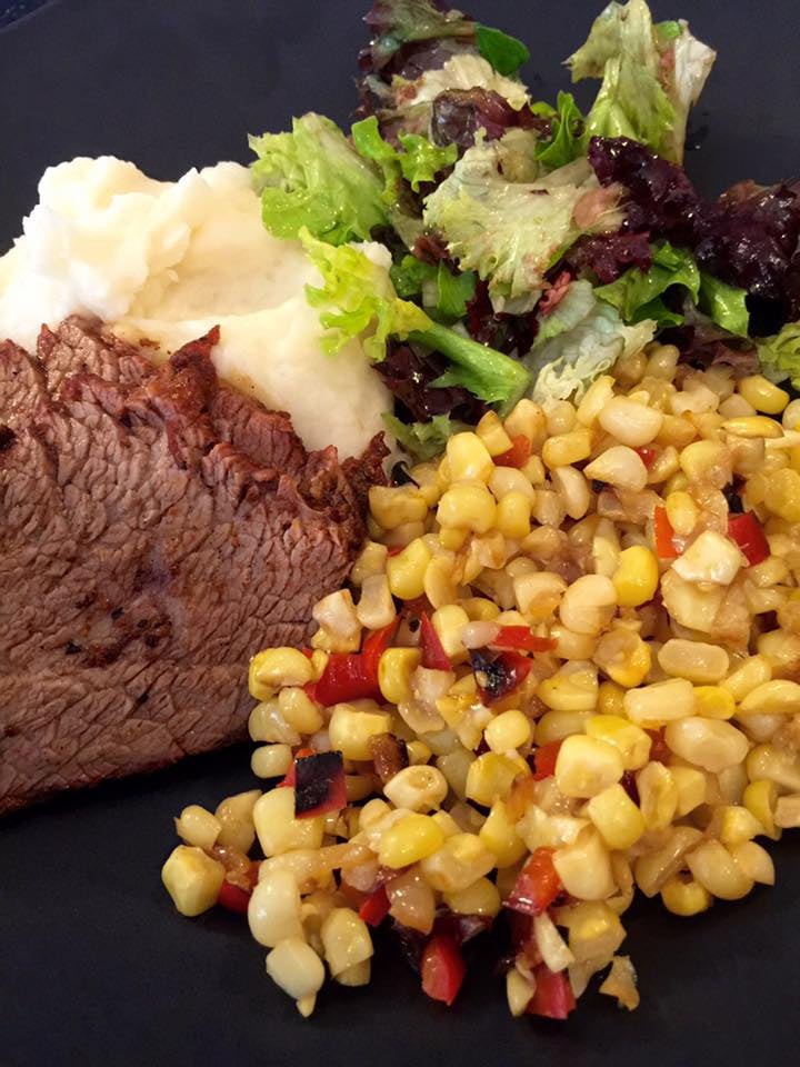 A delicious meal featuring beef, mashed potatoes, corn, and a small salad.