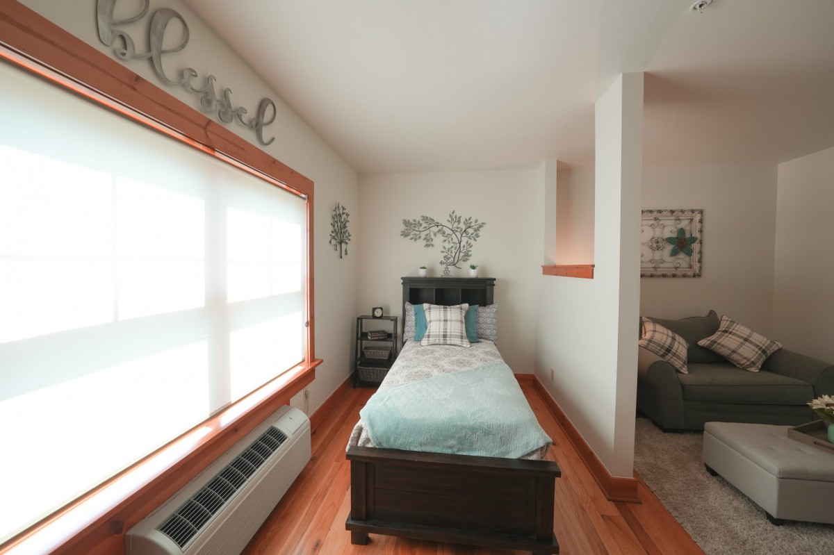 A cozy, minimalist bedroom with a single bed and ample natural light.