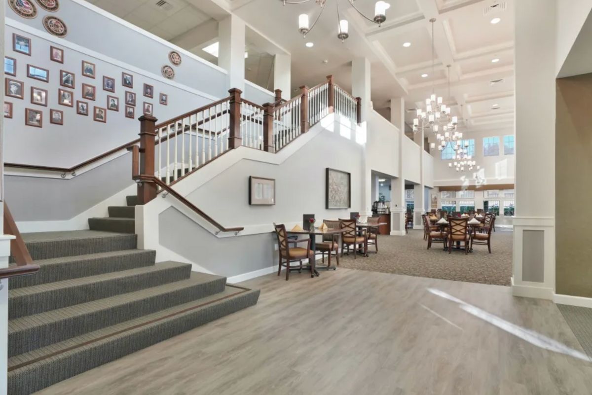 A spacious and elegant lobby featuring a grand staircase, seating area, and chandelier.