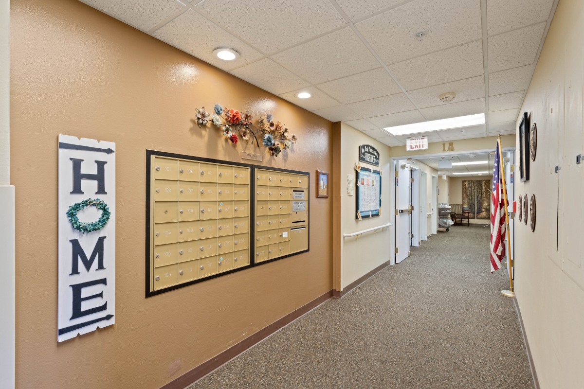 A hallway in an apartment building featuring decorative mailboxes and overhead lighting.