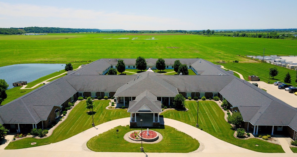 Aerial view of a large mansion surrounded by expansive green fields.