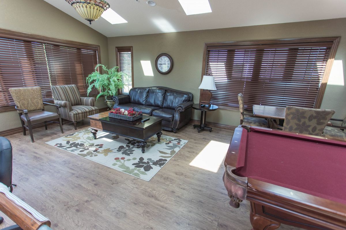 A cozy living room with a leather sofa, coffee table, and pool table.