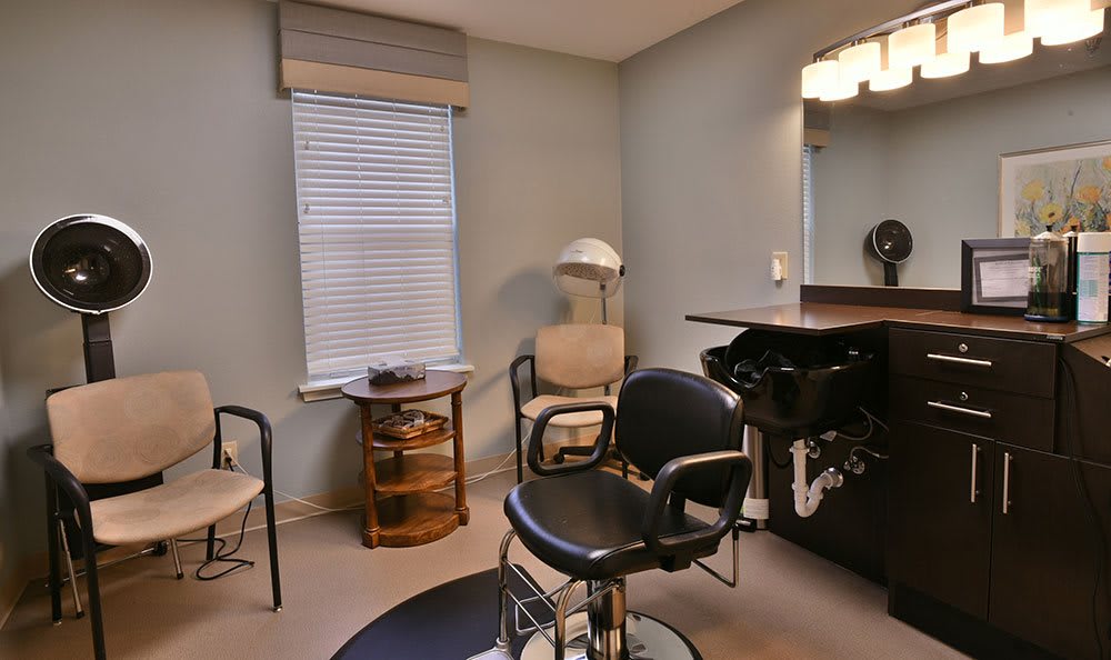 A modern hair salon interior featuring a styling chair, mirror, and hairdressing equipment.
