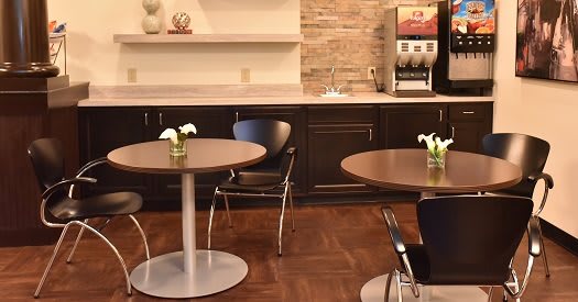 A cozy cafe interior with round tables, chairs, and a coffee machine.