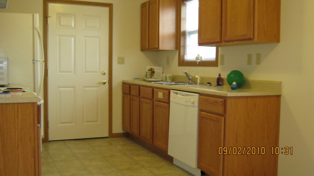 A clean and simple kitchen layout featuring wooden cabinets, a dishwasher, and a sink.