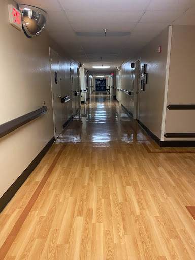 A view down a well-lit corridor with wooden flooring.