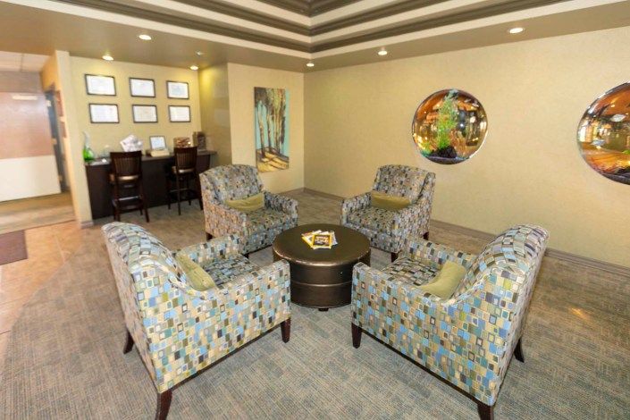 A modern living room with patterned armchairs arranged around a circular table, featuring contemporary artwork on the walls.
