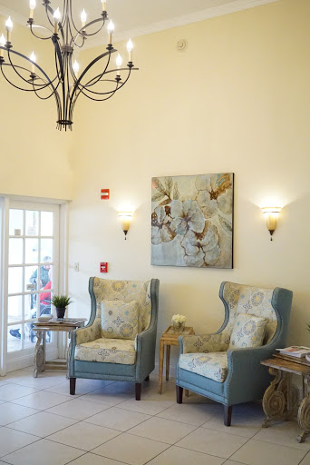 A cozy and elegant lobby area featuring comfortable chairs, tasteful wall art, and a beautiful chandelier.