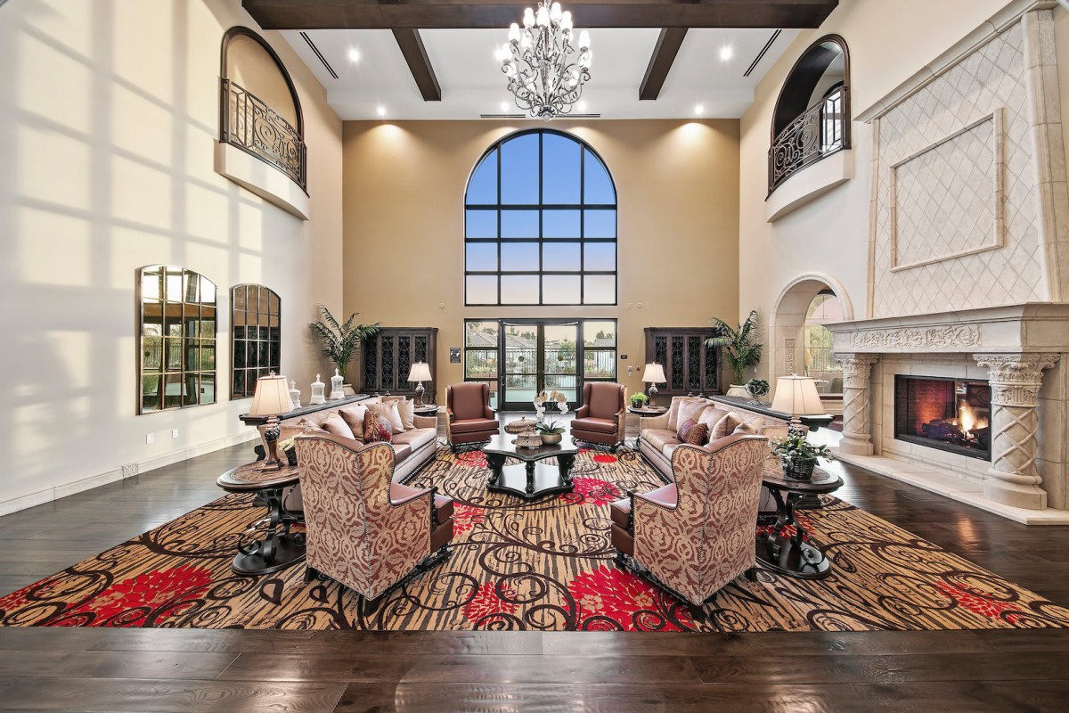 A luxurious living room with high ceilings, a large arched window, and elegant furnishings.