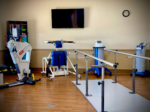 A well-equipped physical therapy room featuring exercise machines, walking bars, and rehabilitation tools.