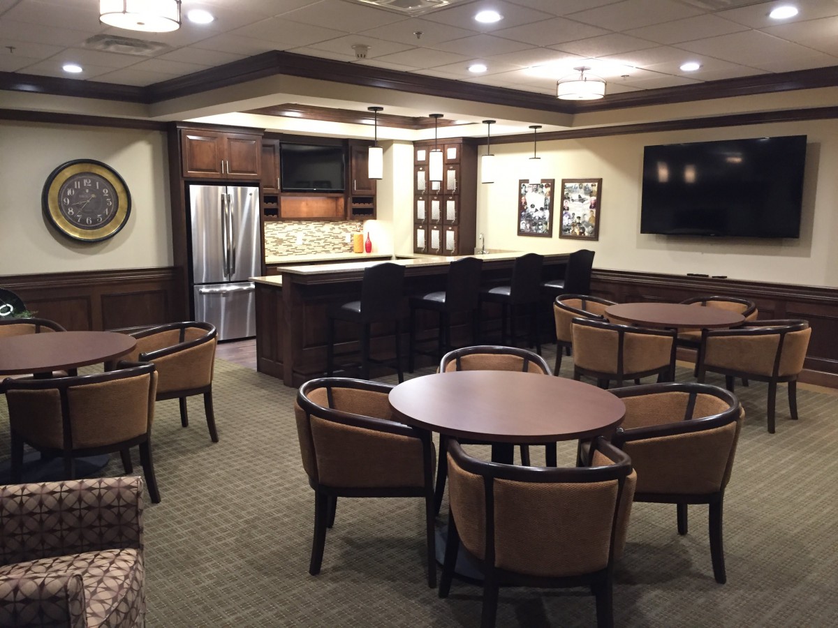 A modern kitchen and seating area featuring a bar counter with chairs and tables.