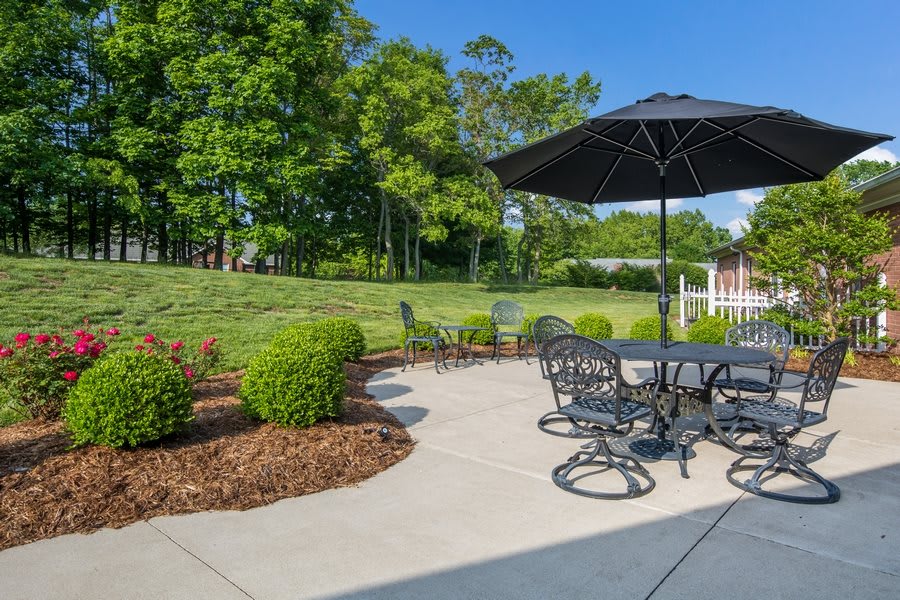 A sunny outdoor patio with furniture and a garden view.