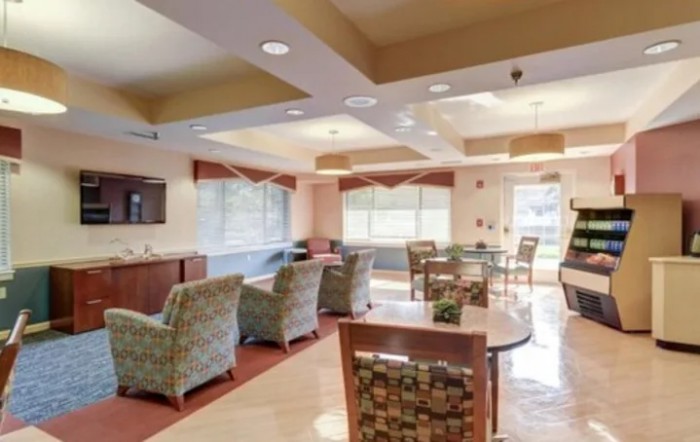 A well-lit lounge with comfortable seating and tables, featuring large windows that allow natural light to enter.