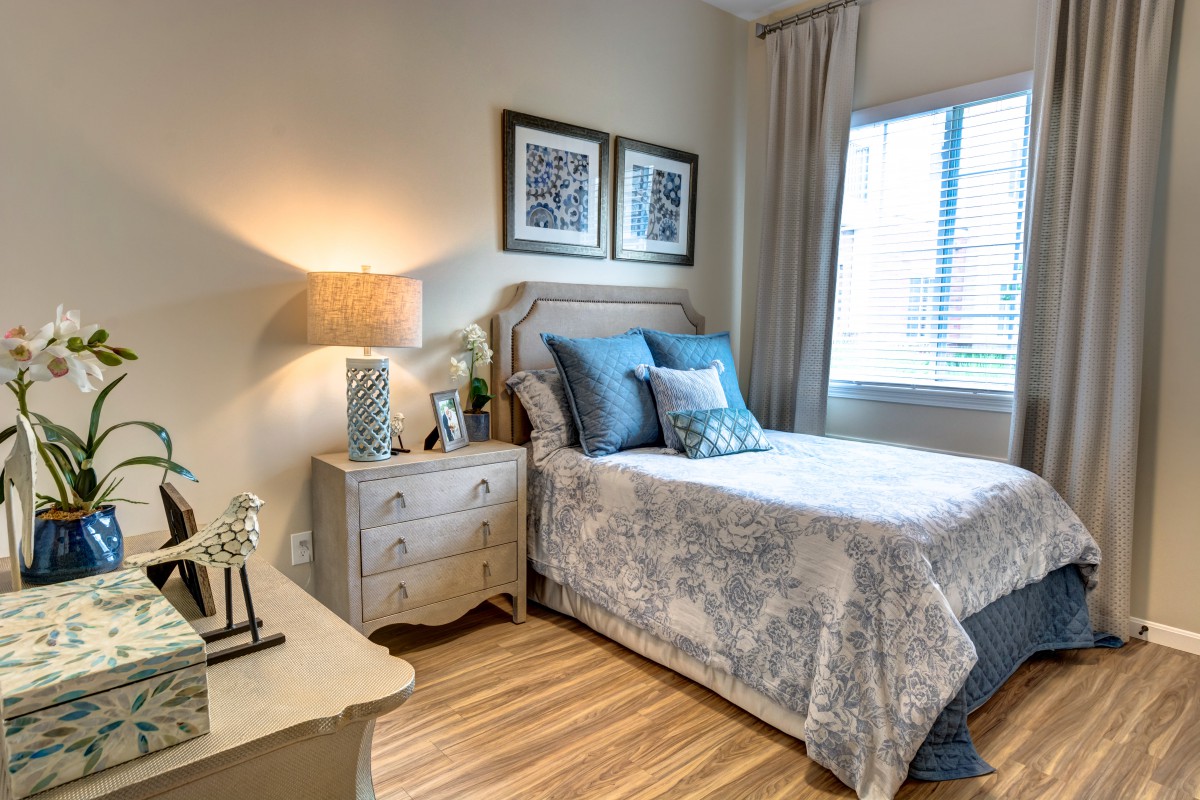 A cozy bedroom with a neatly arranged bed, decorative pillows, and soft lighting from a lamp on the nightstand.