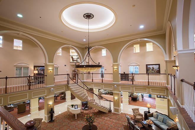 A luxurious hotel lobby featuring a grand staircase and an ornate chandelier.