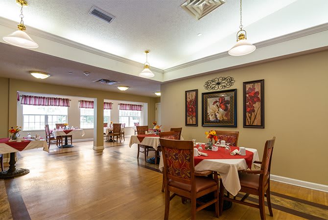 A well-decorated dining room with wooden tables and chairs, featuring elegant wall art and ample lighting.