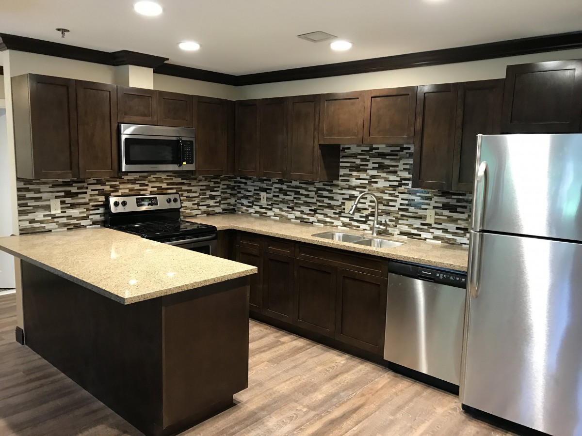 Modern kitchen with dark cabinetry, stainless steel appliances, and patterned backsplash.