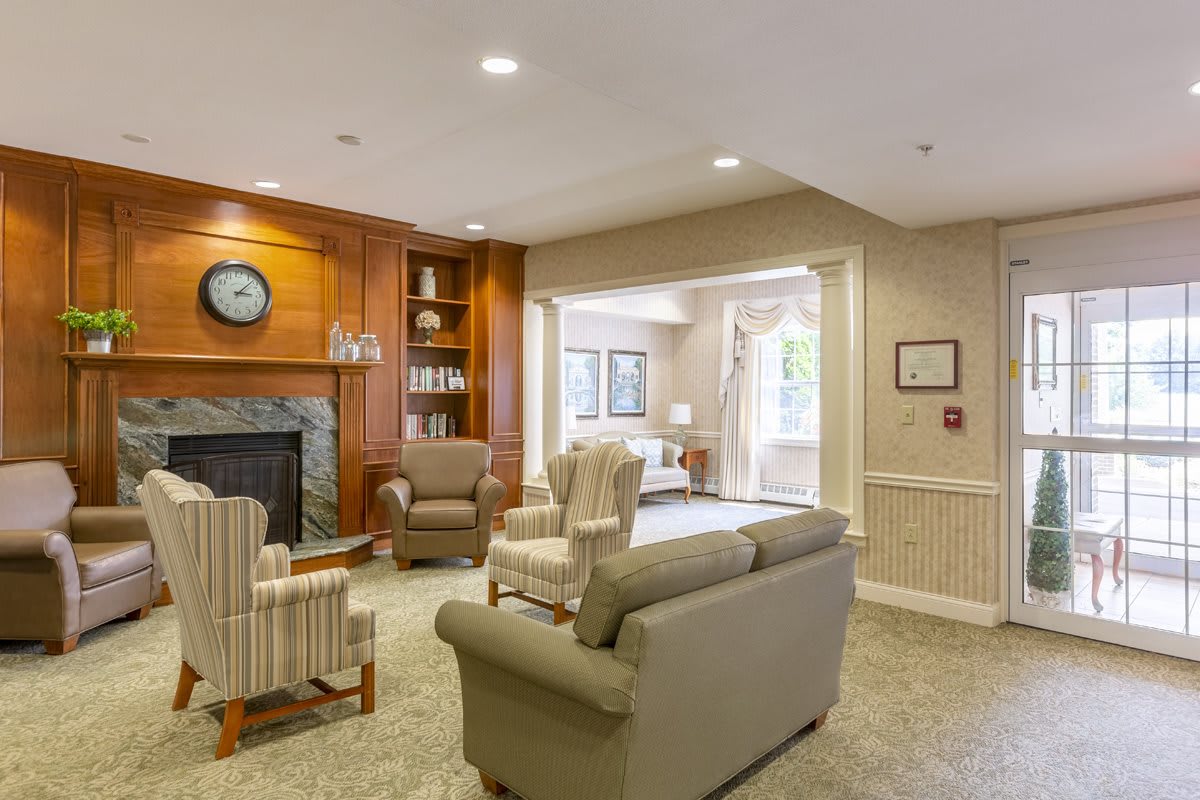 A cozy living room with a fireplace, armchairs, and a sofa, featuring elegant bookshelves.