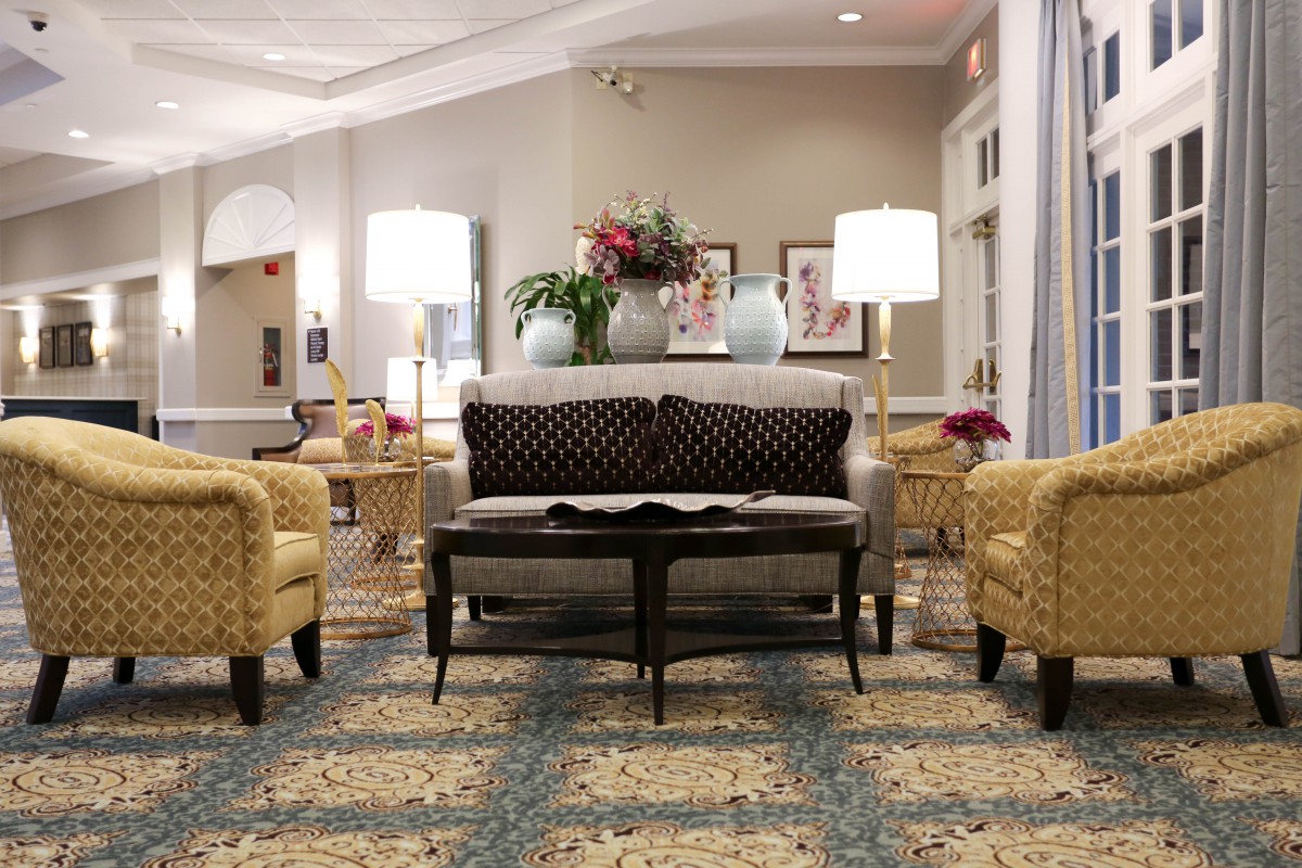 A cozy living room setup with a sofa, armchairs, and a coffee table, illuminated by table lamps.