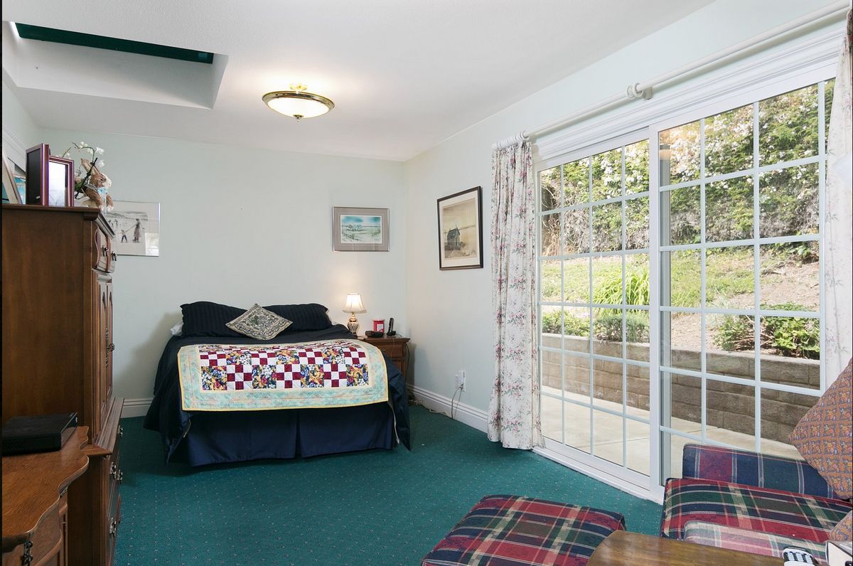 A cozy bedroom with a large bed, colorful quilt, and sliding glass doors leading outside.