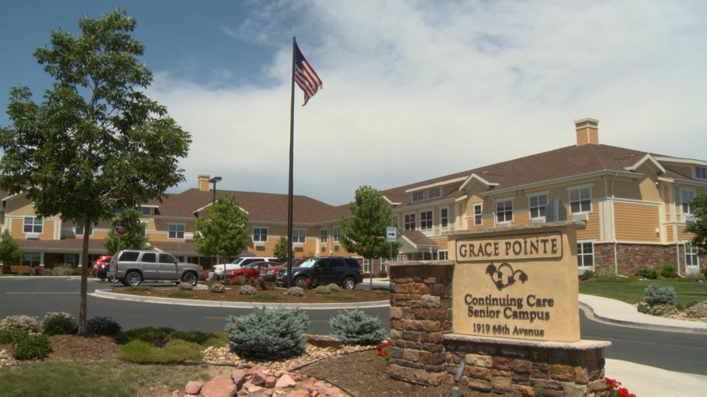 A view of a senior living center with an American flag and a sign in the foreground.