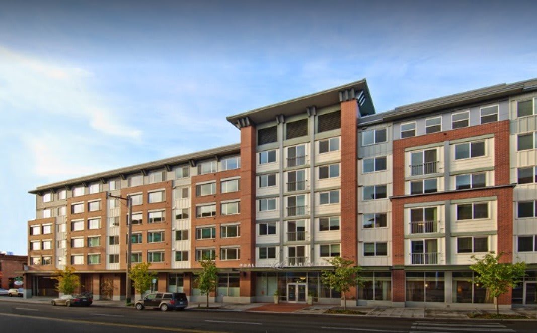 A modern multi-story apartment building with a combination of brick and glass facade.