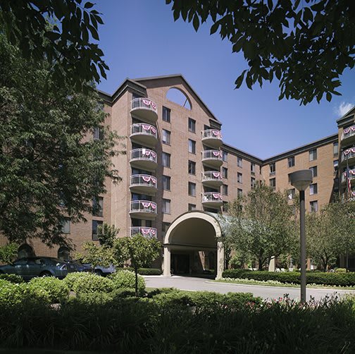 A multi-story apartment building with landscaped surroundings and a central entrance.