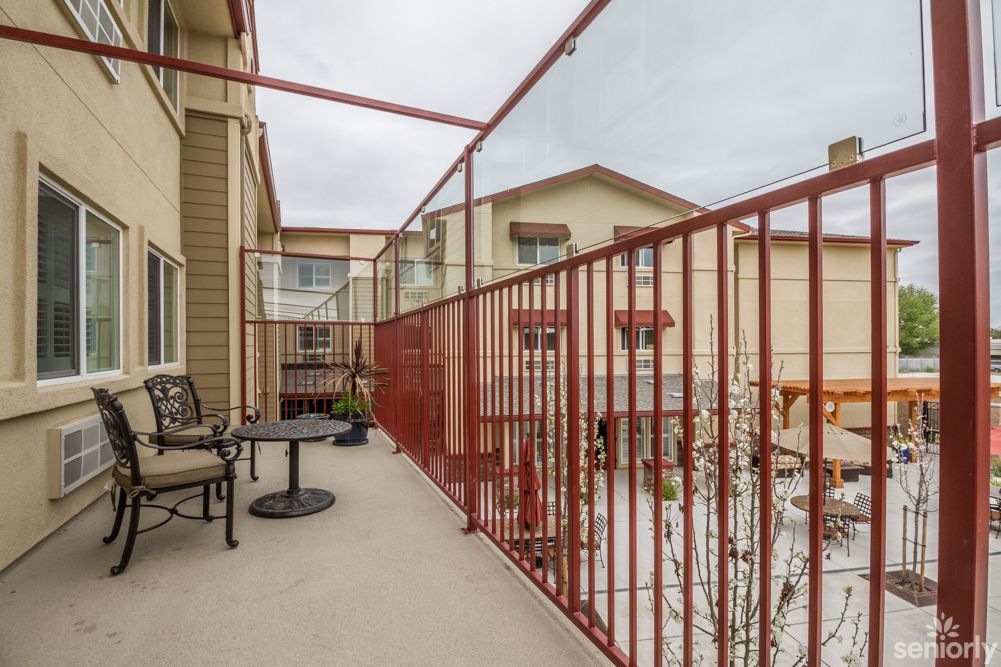 A cozy balcony with red railings, featuring a small table and chairs for relaxation.
