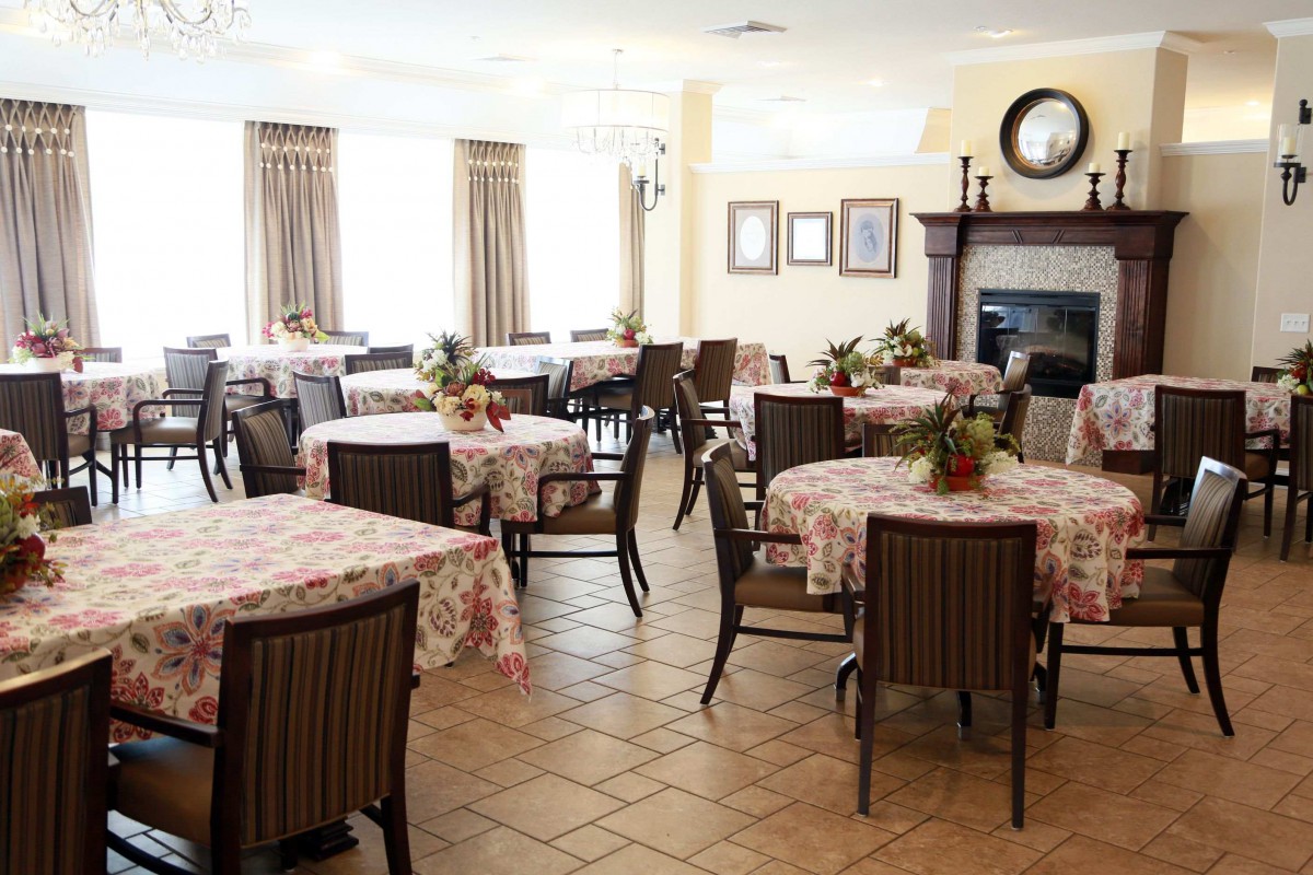 An elegant dining room with several tables covered in floral tablecloths, each adorned with a flower arrangement.