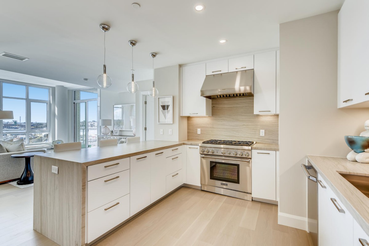 A modern kitchen featuring stainless steel appliances, white cabinets, and a spacious island with pendant lighting.