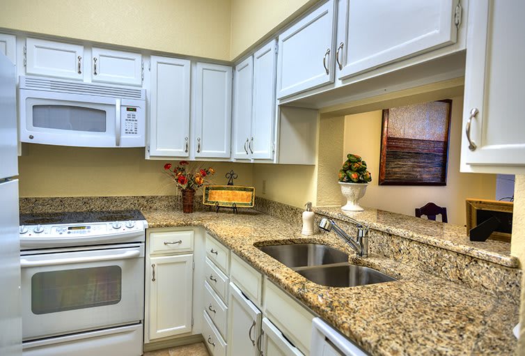 A modern kitchen featuring white cabinets, granite countertops, and a stainless steel sink.
