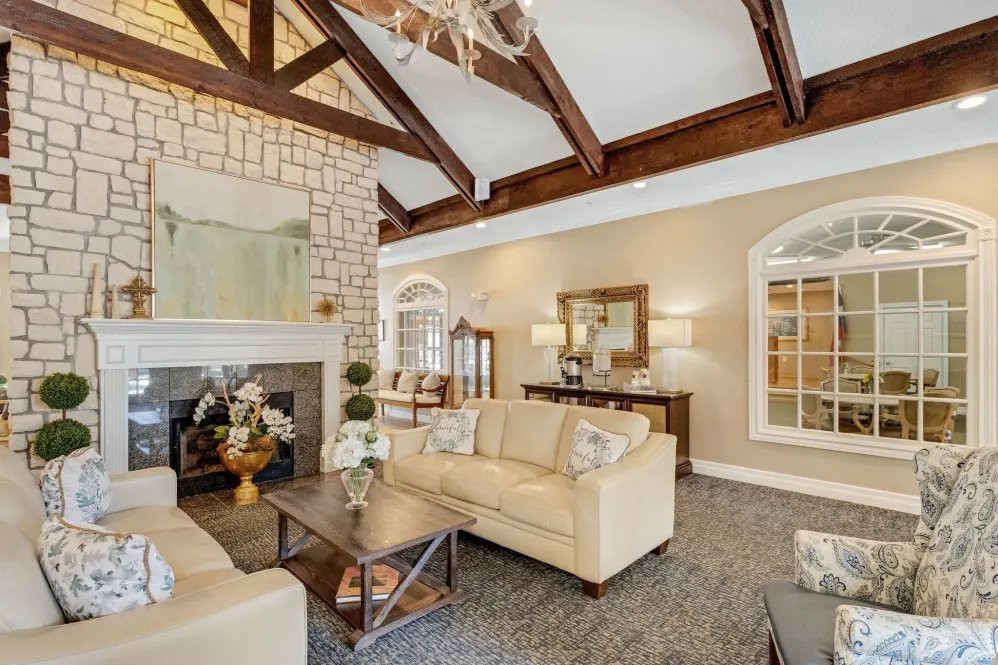 A spacious living room featuring exposed wood beams, a cozy fireplace, and elegant furnishings in neutral tones.