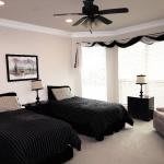 A modern bedroom with twin beds featuring a black and white decor scheme, illuminated by natural light from large windows.