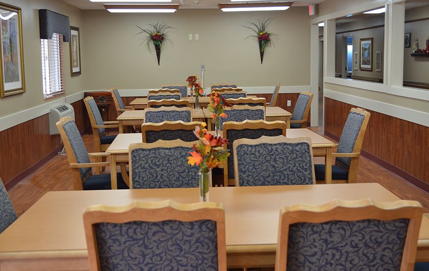 An empty dining area with neatly arranged tables and chairs, adorned with floral centerpieces.