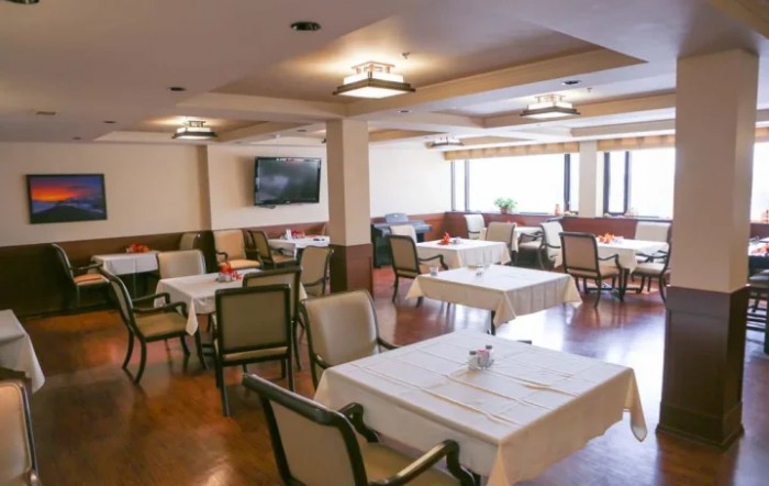 An empty restaurant dining area with neatly arranged tables and chairs.