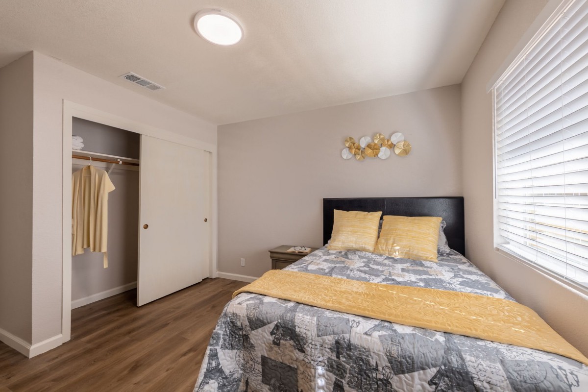 A cozy bedroom with a bed, quilt, pillows, and an open closet.