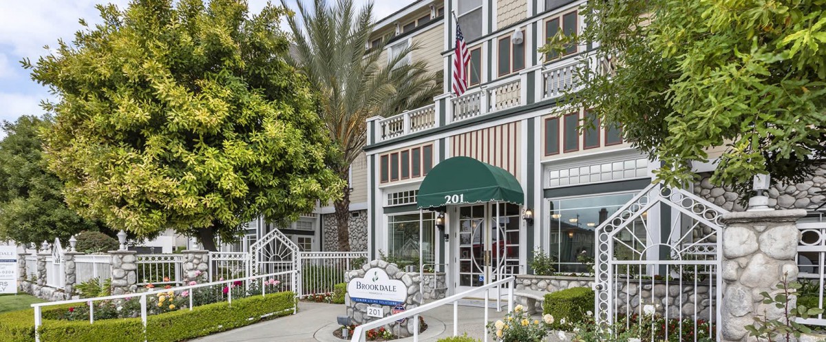 A hotel entrance with green awnings and an American flag displayed.