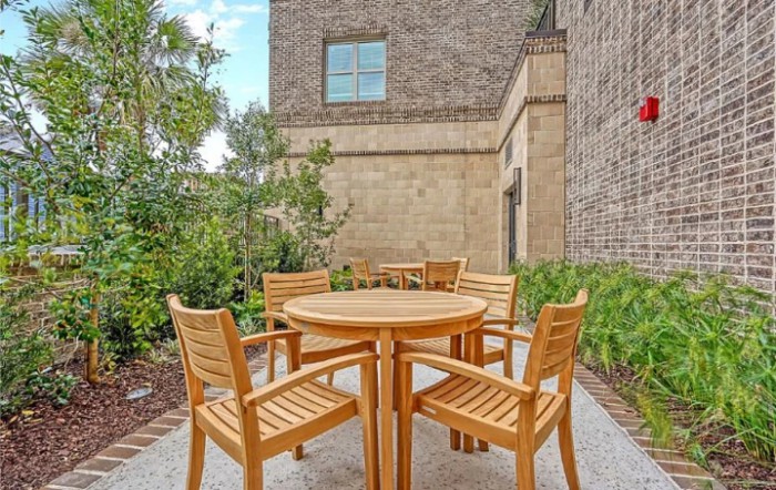 A cozy outdoor seating area with a wooden table and chairs set against a brick wall.
